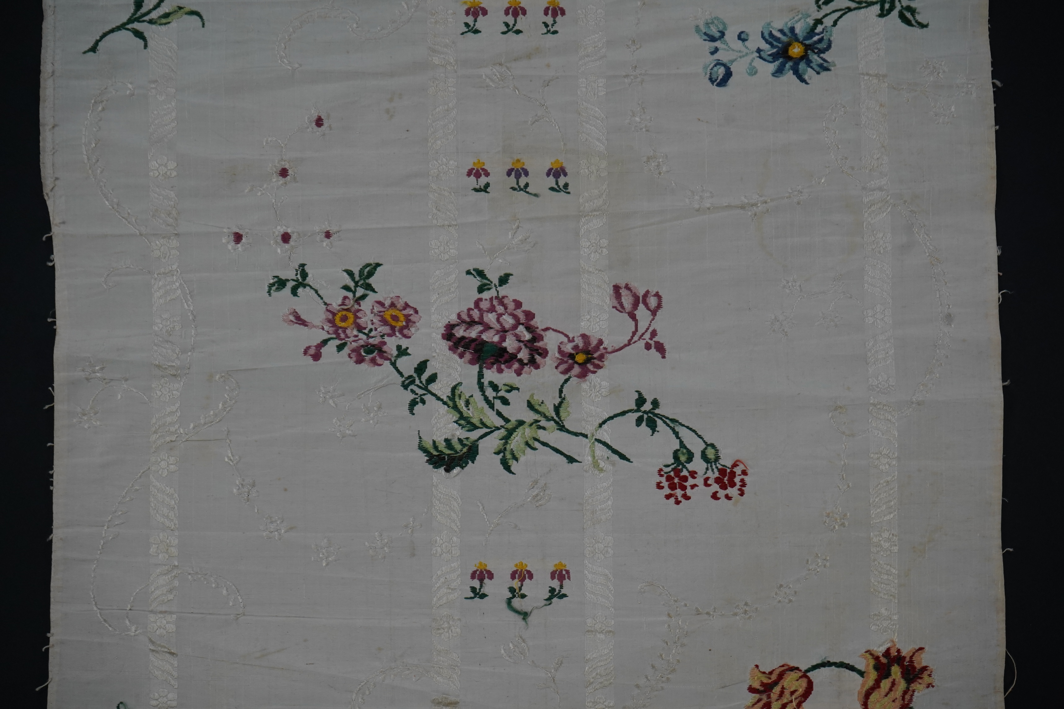 A length of 18th century short loom hand woven Spitalfields silk dress fabric, woven in cream silk with all over multicoloured spot floral motifs in a large repeat. 82cm repeat, total length of fabric 100cm x 48.5cm wide